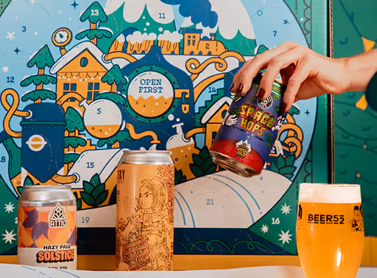 A hand pulling a can from a door, with cans and the Beer52 glass in front