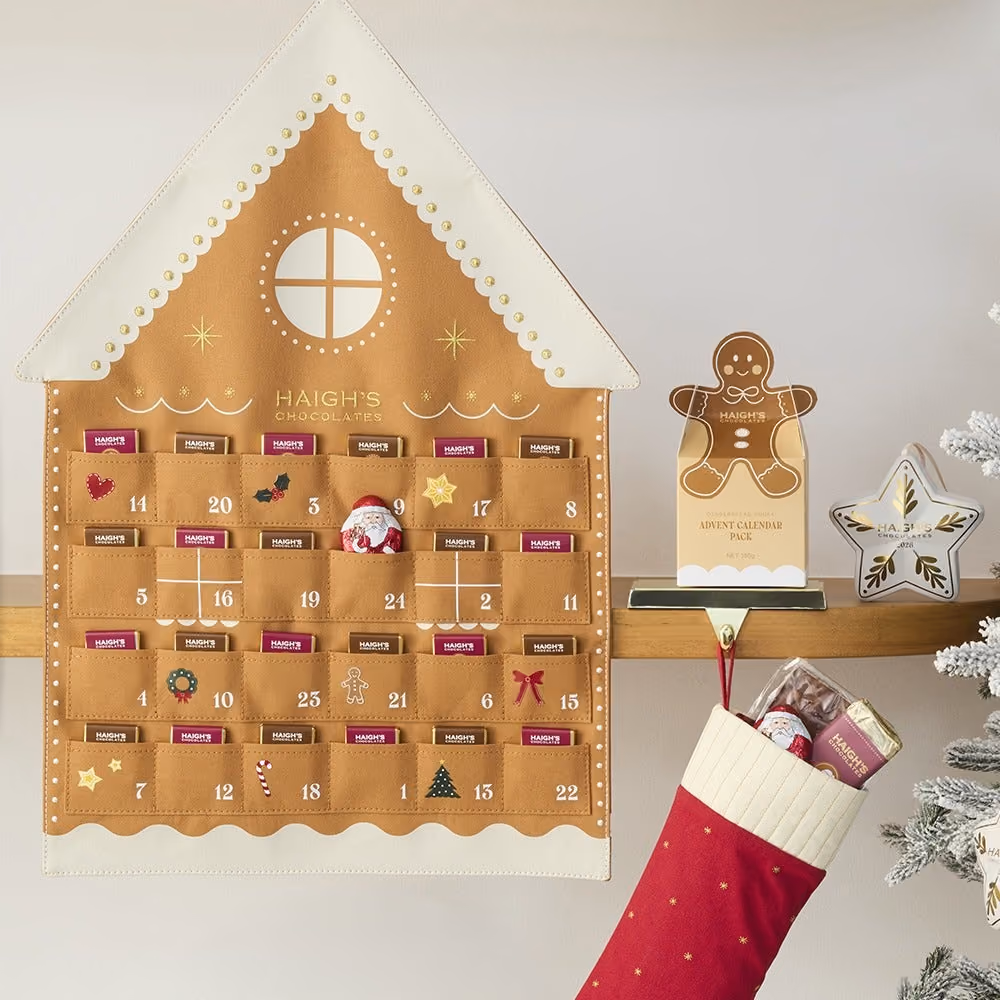 The house hung on a wall with chocolates in its pockets beside a mantel and stocking