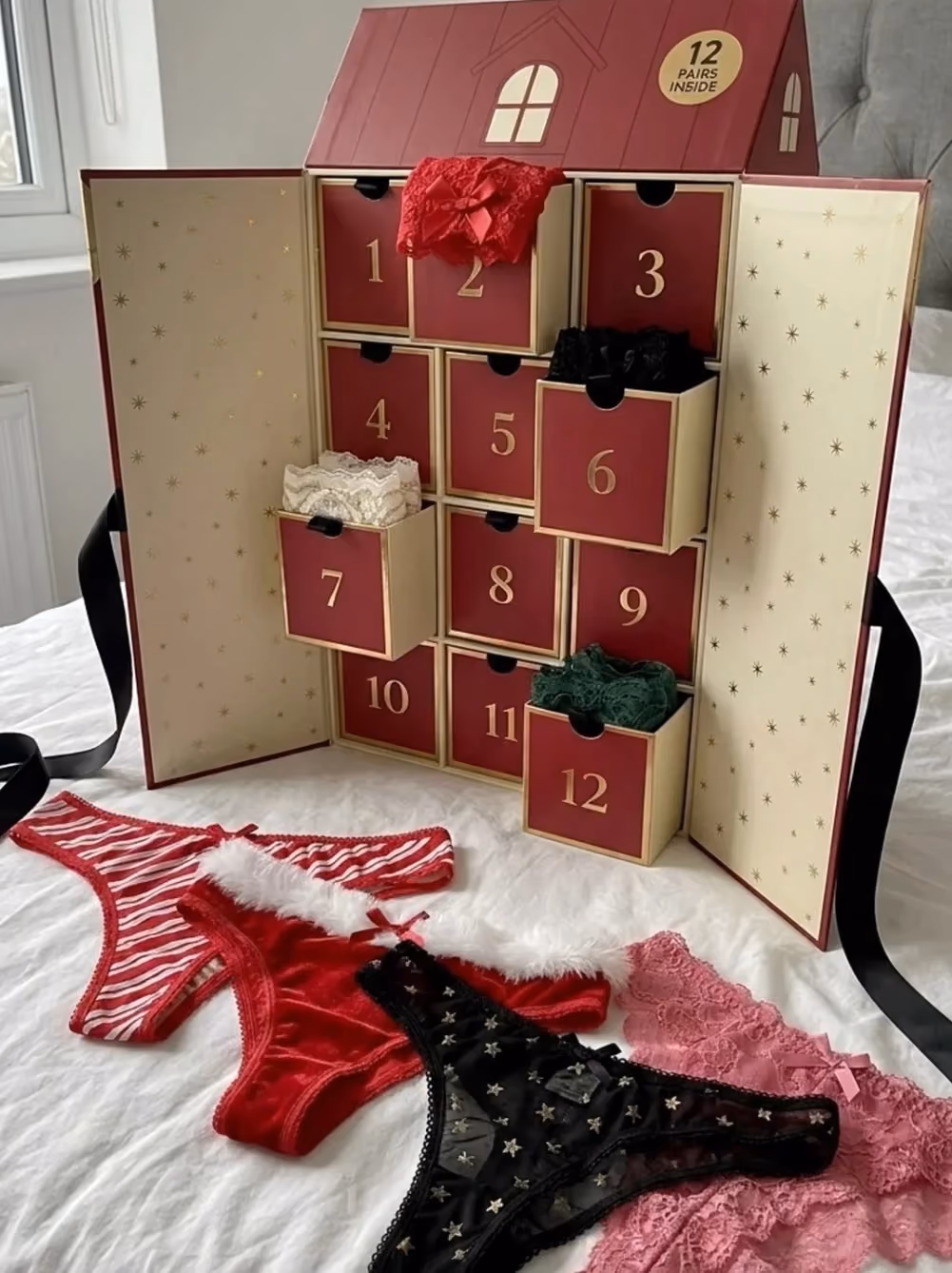 The house box open on its twelve numbered drawers, with lace and velvet thongs laid in front