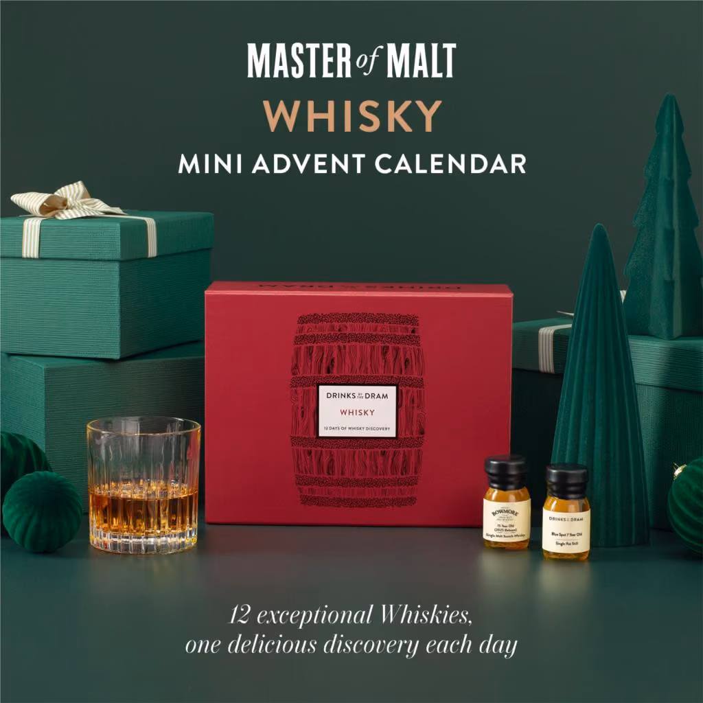 The red barrel-printed mini box on a green set beside a tumbler and two drams