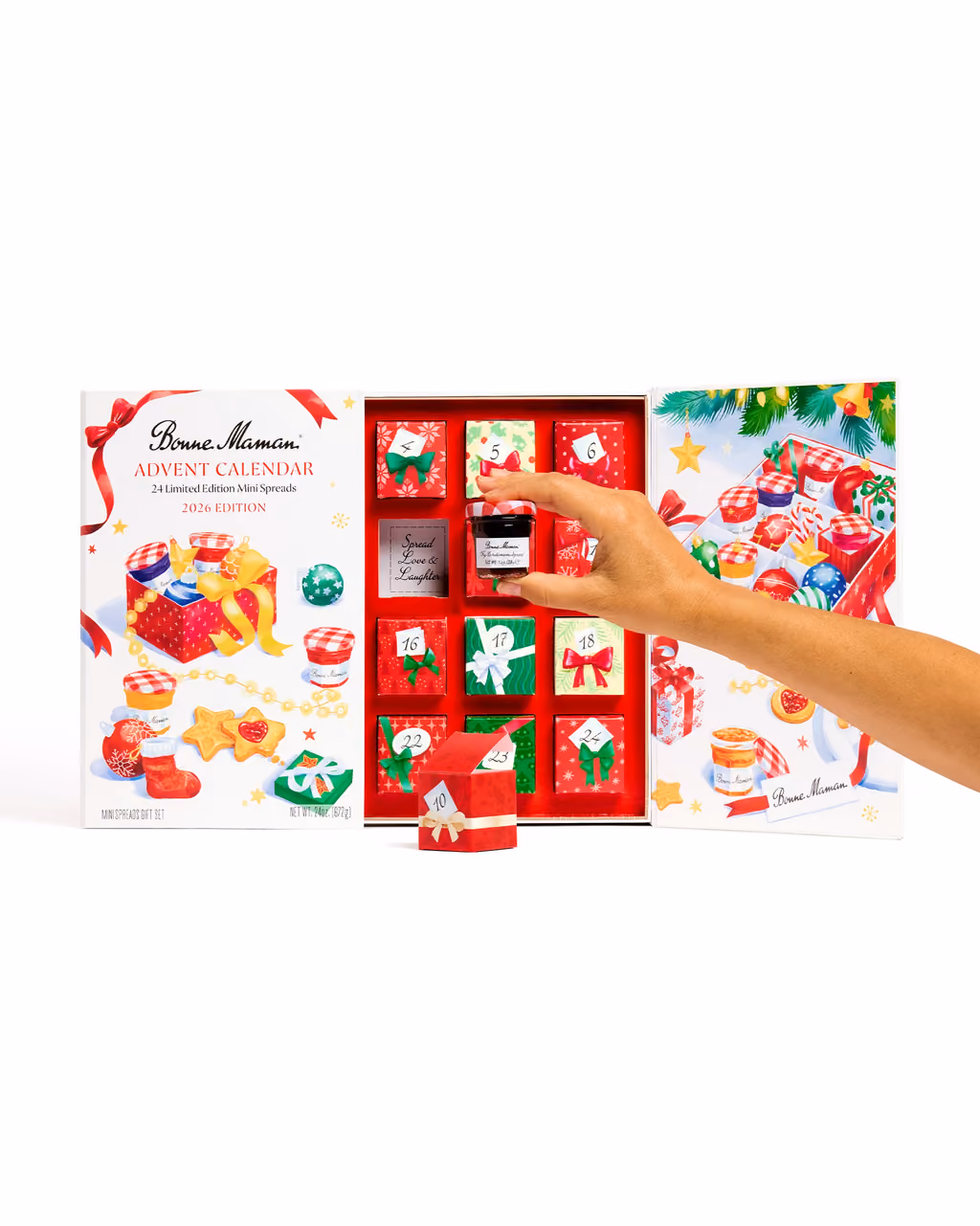 The Bonne Maman 2026 calendar half open, a hand lifting one of the red mini boxes from its door