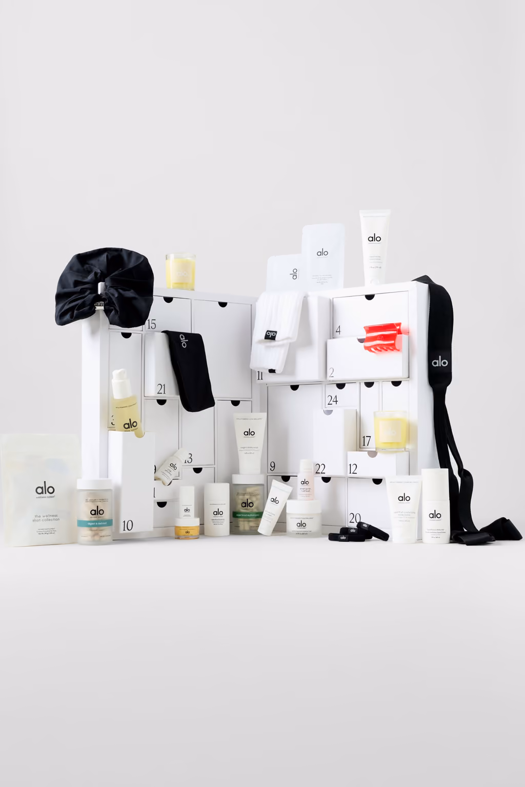 The white Alo box open with its skincare bottles, scrunchie, eye mask and bag arranged around it