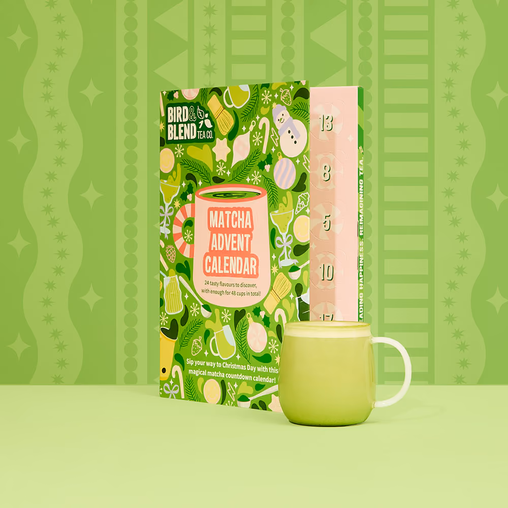 The box half open with a matcha latte in a green mug beside it