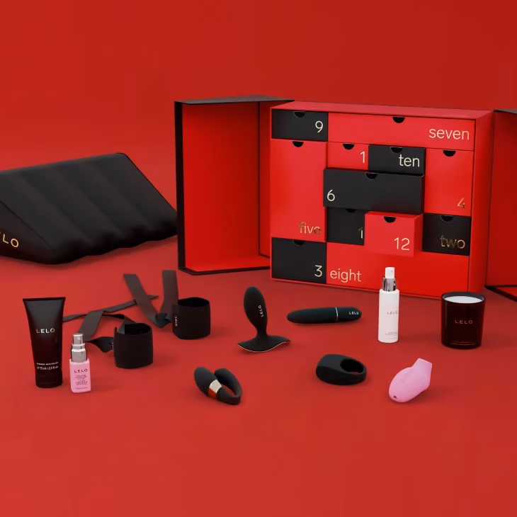 The twelve pieces laid out in front of the open red box, the sex pillow behind them