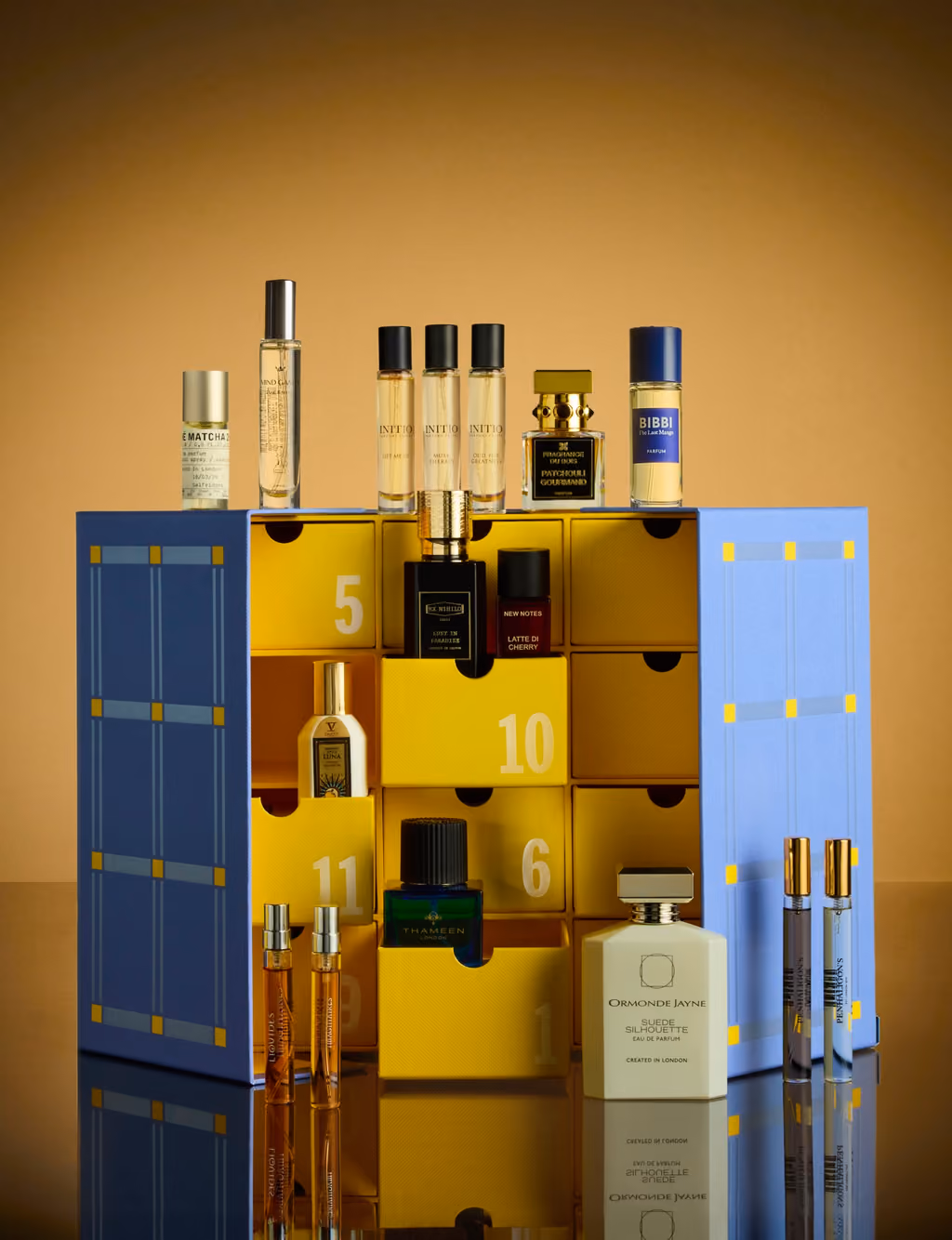 The box open on a mirrored surface under warm light, bottles in its yellow drawers