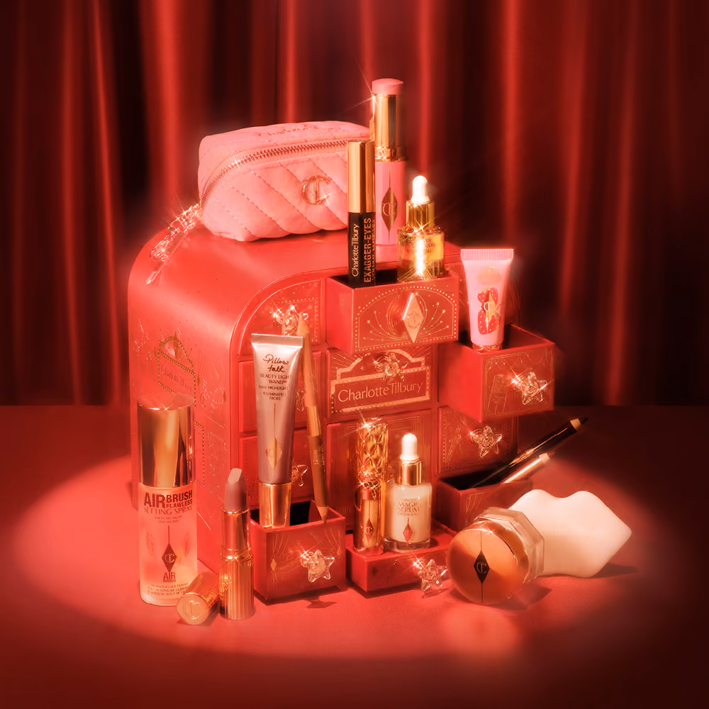 The red Hollywood Beauty Wonderland chest with its makeup and skincare stacked on top, against a red curtain