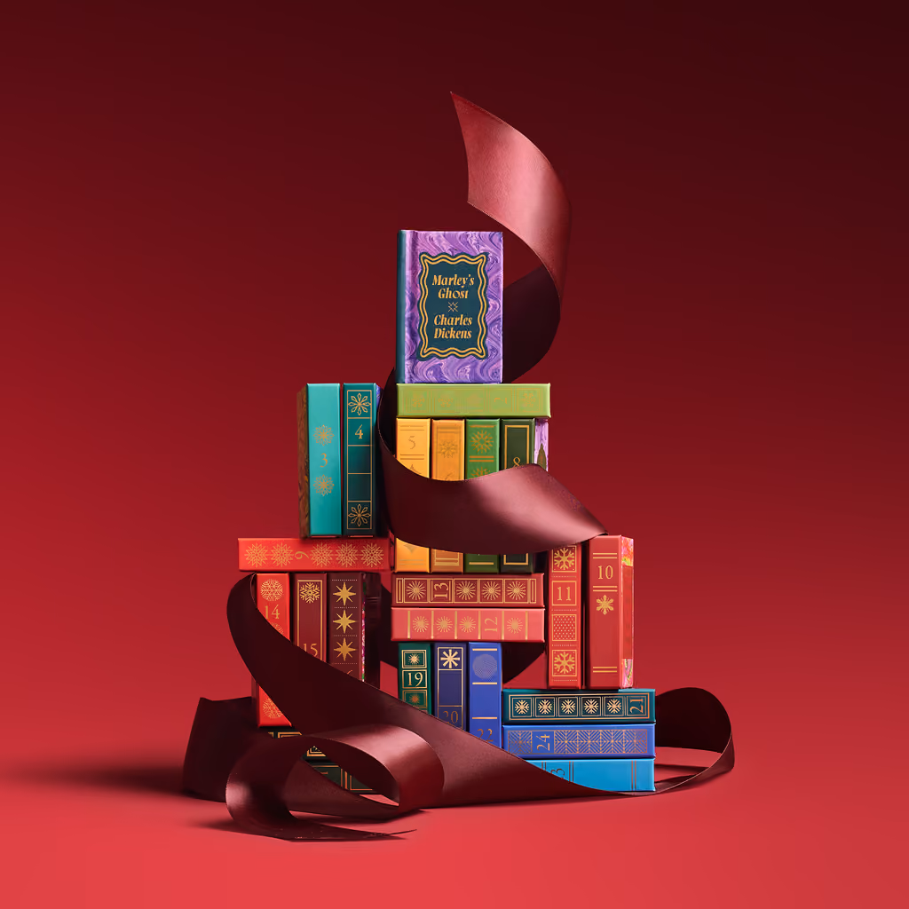 Miniature books stacked with a burgundy ribbon on red