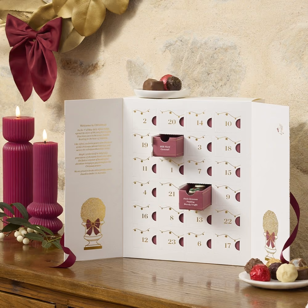 The opened cabinet beside burgundy candles with chocolates on a plate