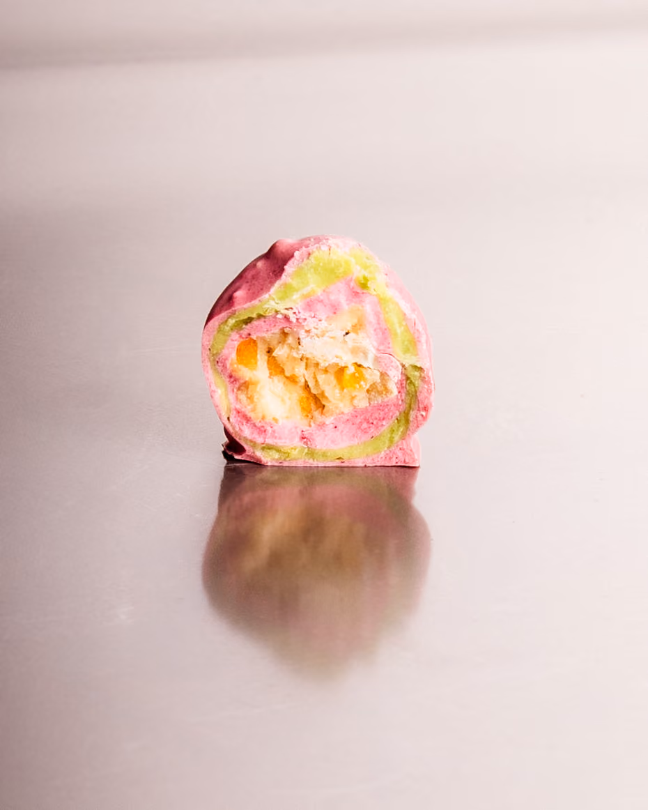 A pink and green chocolate cut open on a crumbly filling
