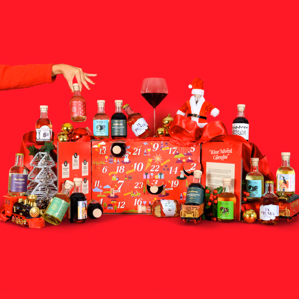 The open calendar with 24 mini bottles and two glasses spread across a red table