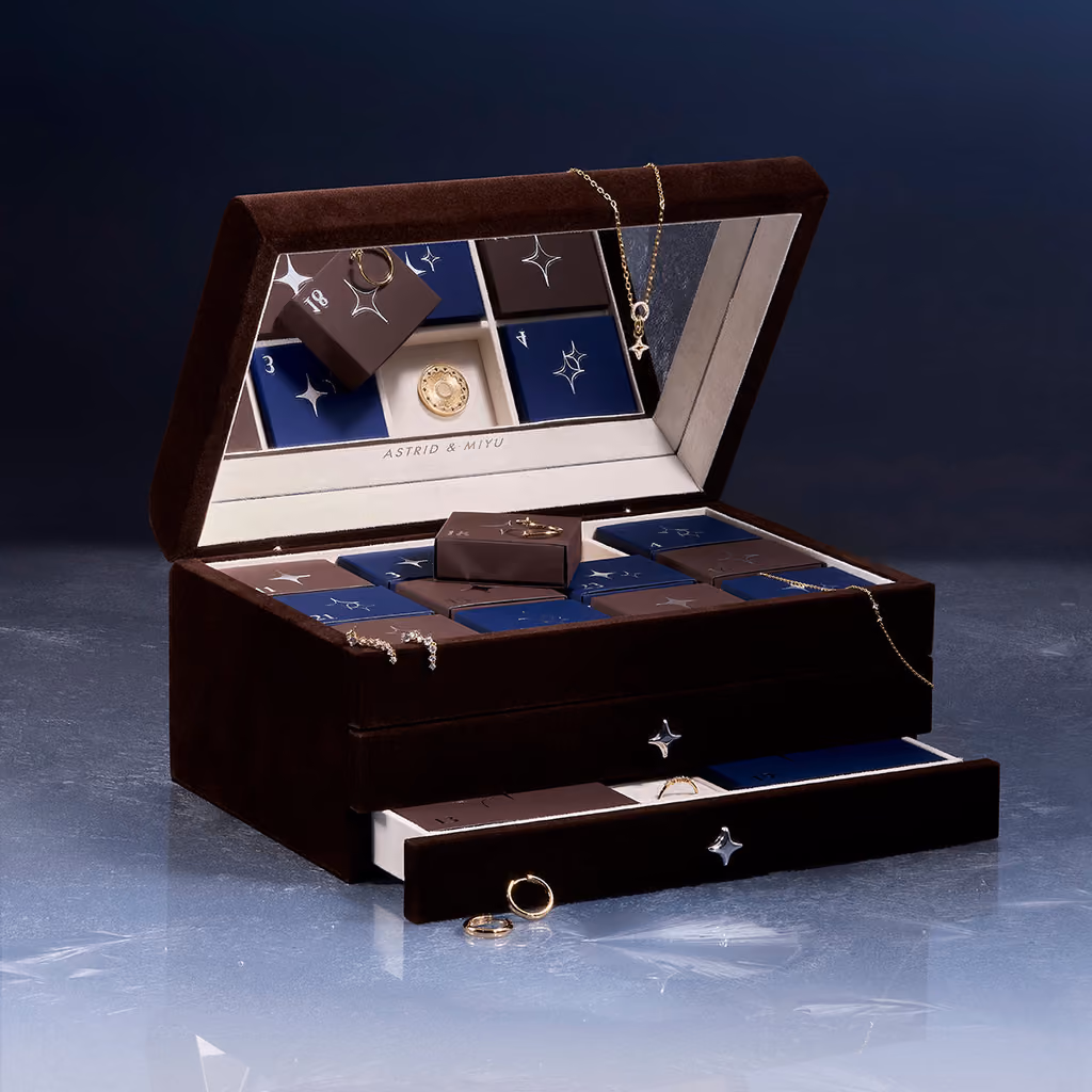 The suedette box open with its mirror, a lower drawer pulled out and a few gold pieces draped over it