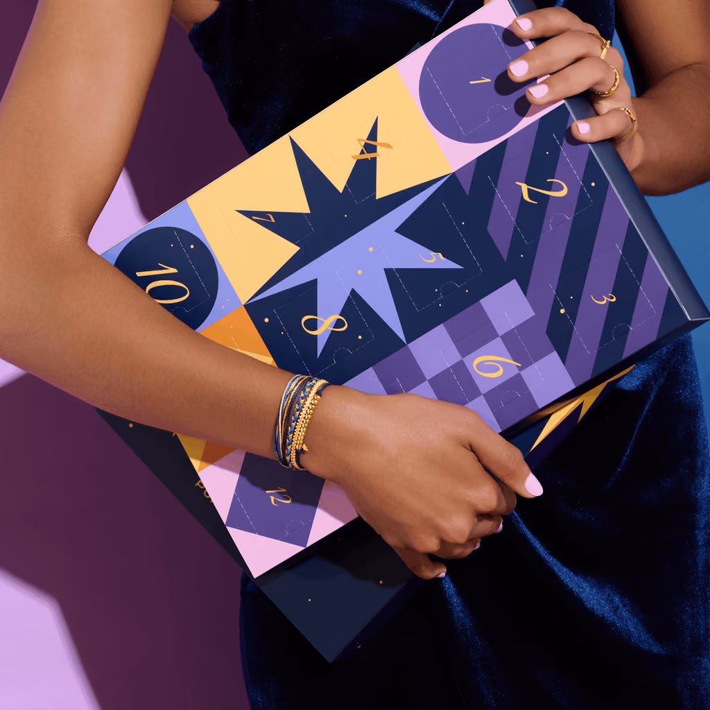 The closed calendar held under an arm, a stack of string bracelets on the wrist
