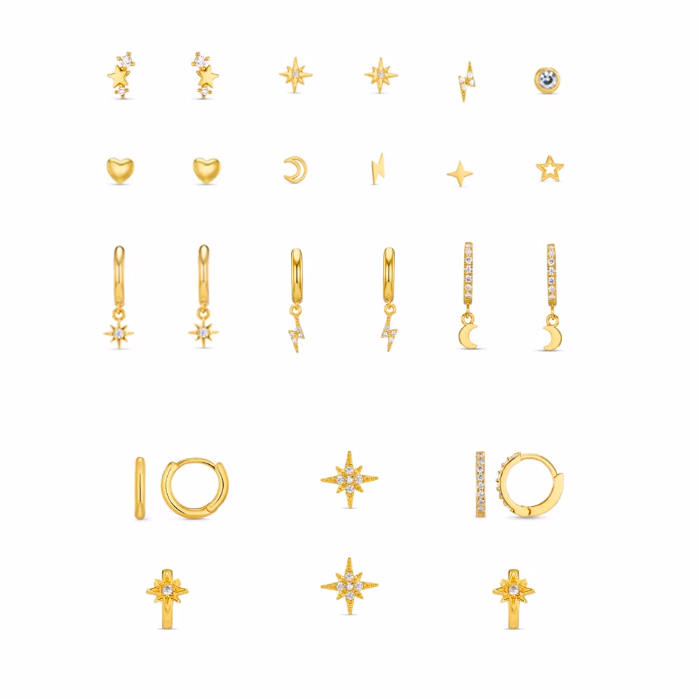 Gold starburst, moon, heart and lightning bolt studs and charm hoops laid out on white