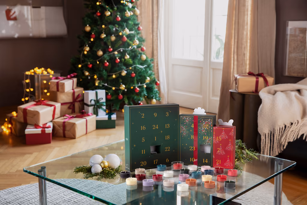 The open box with the 24 coloured tea lights and the glass holder in front