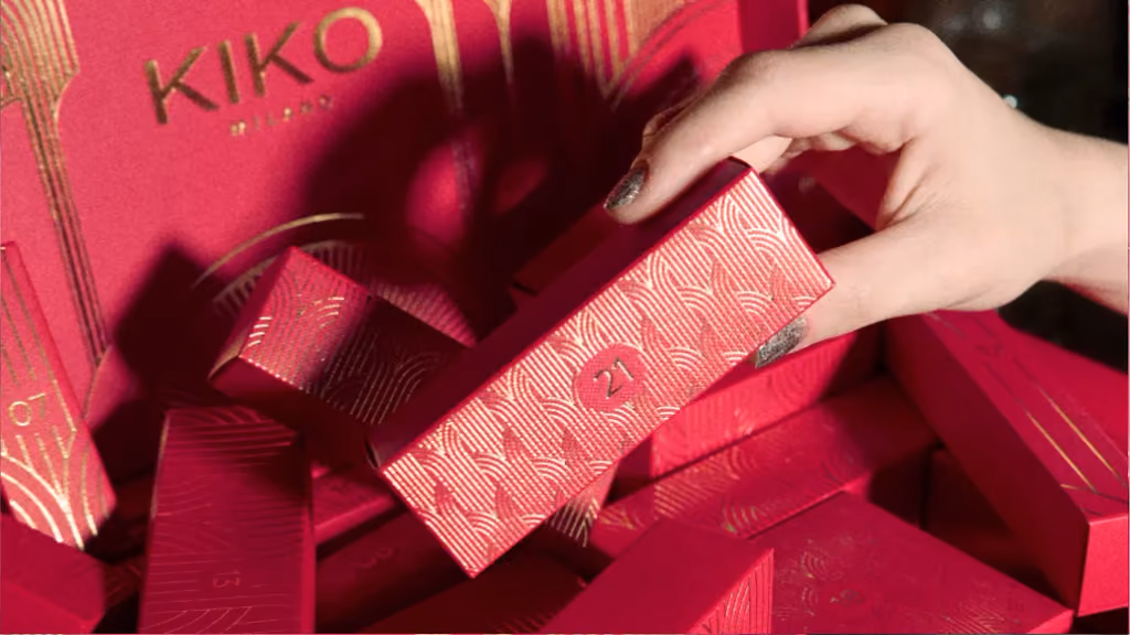 A hand lifting one of the red Twist 'N Twinkle door boxes from a pile of them